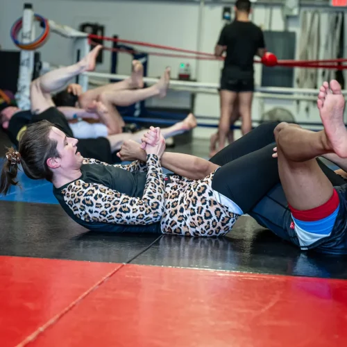 A Brazilian Jiu-Jitsu class practicing submission techniques at Elite Martial Arts, with students drilling an armbar on the mats.