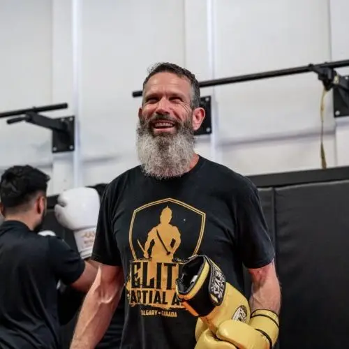 Smiling man in boxing gloves trains in a Muay Thai course in Calgary