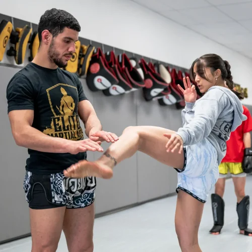 Instructor Abdou guiding a student through a Muay Thai roundhouse technique at Elite Martial Arts.