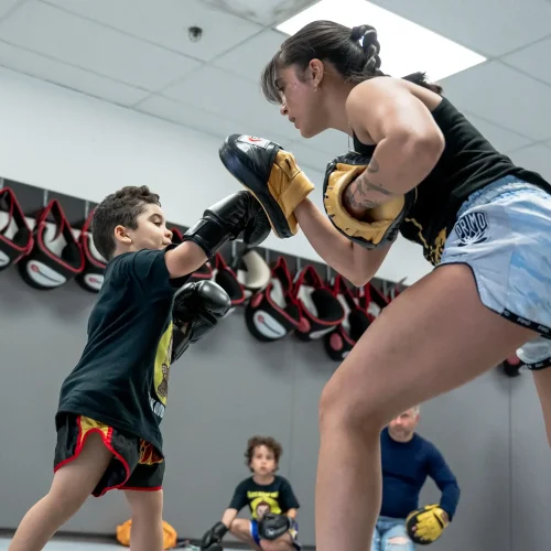 Kids Muay Thai in Shepard features a boy practicing striking techniques with his instructor