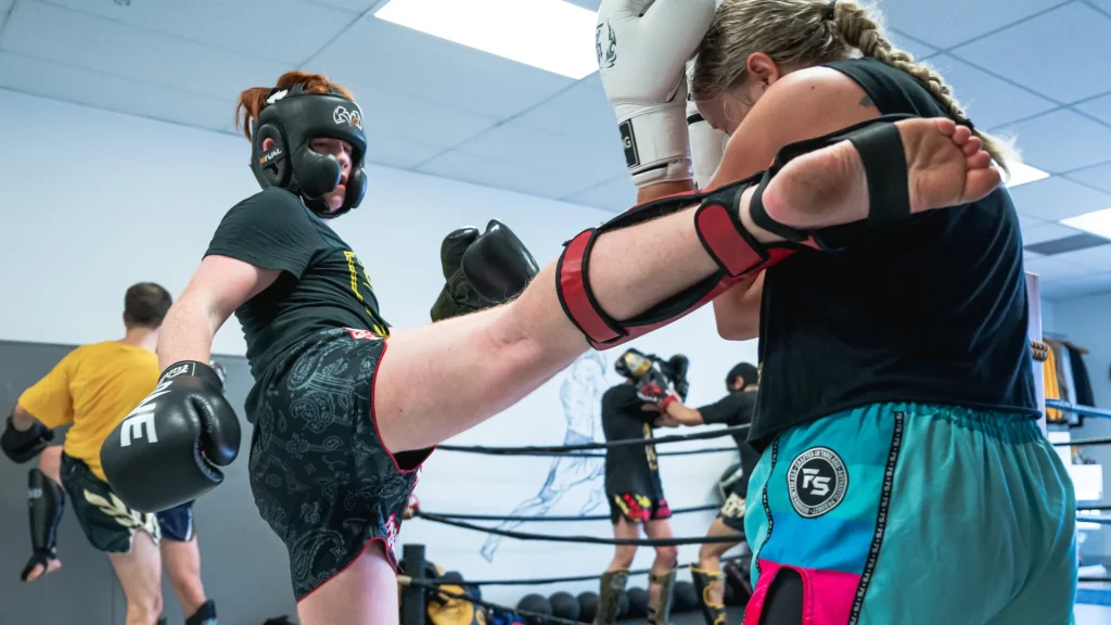 Adult Muay Thai Calgary athletes spar, showcasing kicks and defensive techniques