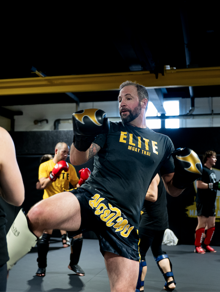 Teen martial arts Calgary fighter performs a knee strike during training with teammates