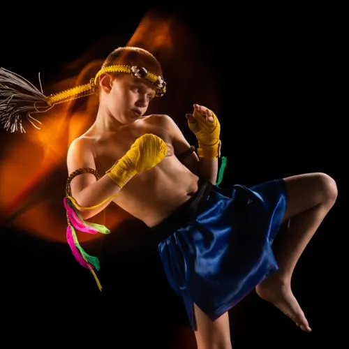 Kids Muay Thai in Flint Road features a young fighter demonstrating a powerful kicking pose with energy and determination
