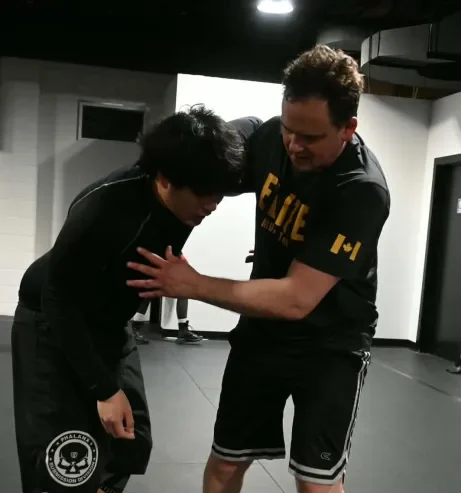 Youth jiu jitsu trainees practice grappling techniques with coach assistance