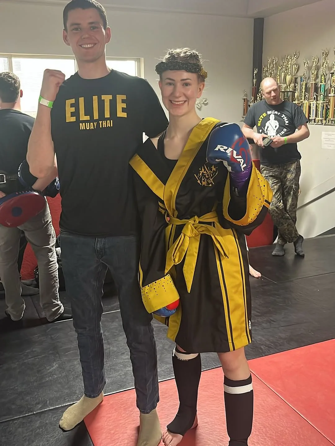Teen muay thai practitioners proudly pose in martial arts attire at their training facility
