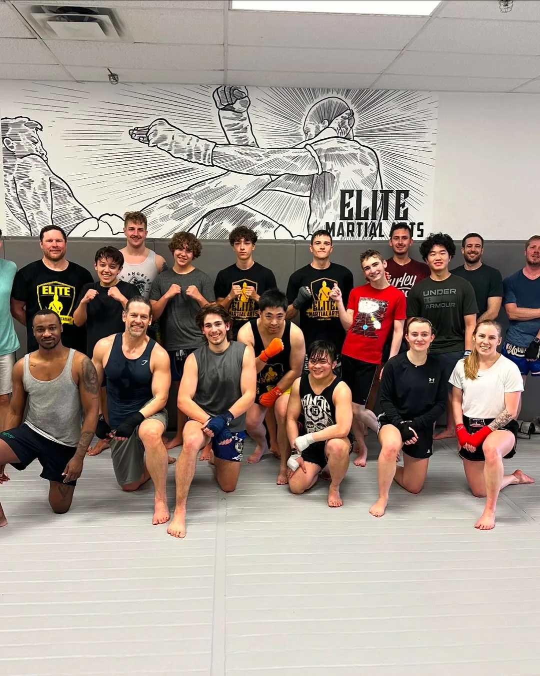 A diverse group of martial artists poses together in a training studio