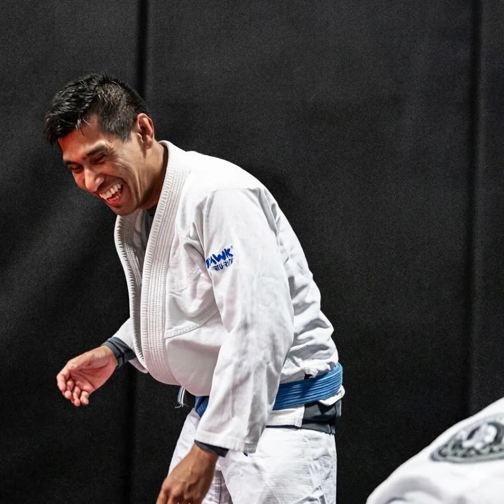 A person wearing a jiu-jitsu gi laughs during a training session