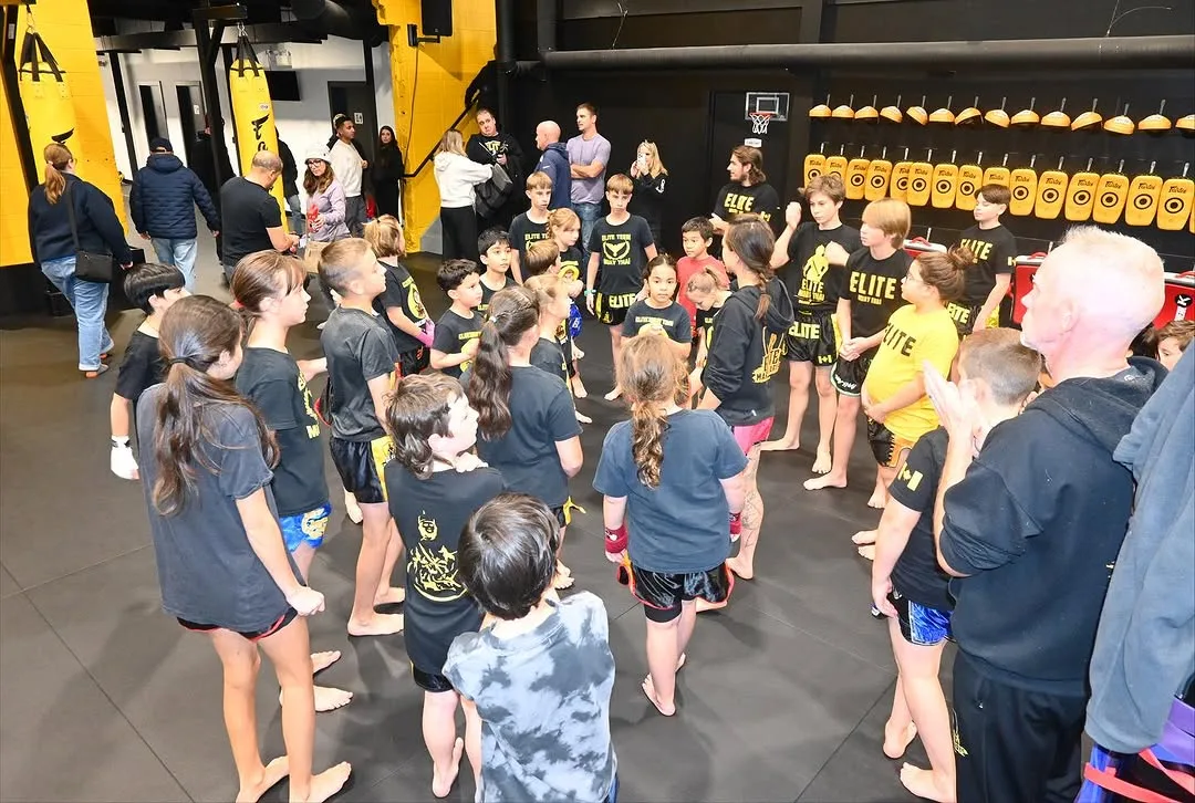 A group of children in matching shirts gathers in a training facility