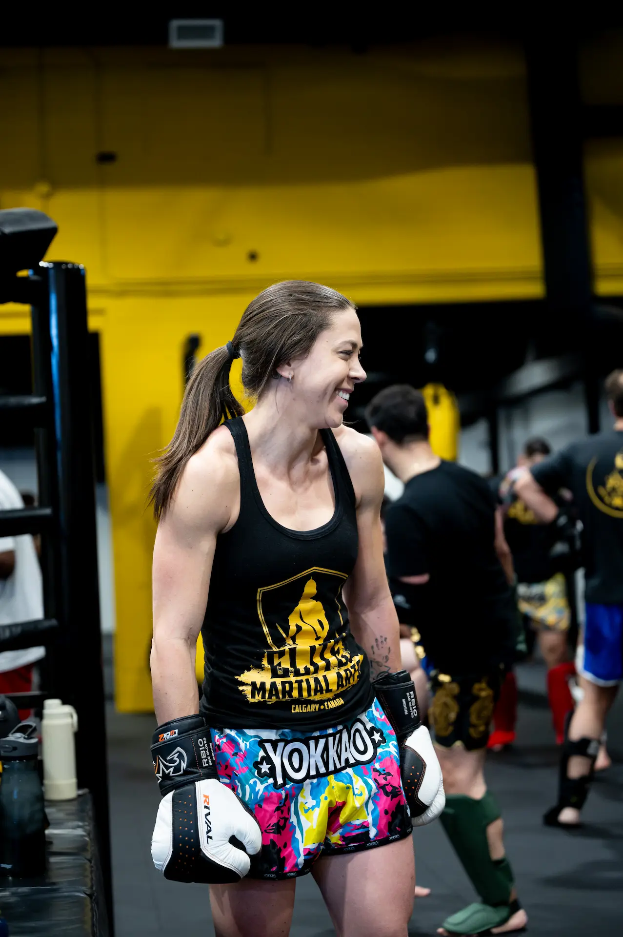 A woman in boxing gear smiles while training in a gym