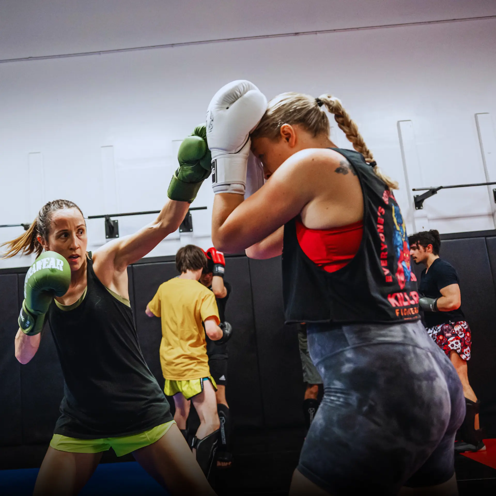Two women spar in a boxing gym, showcasing their skills and techniques